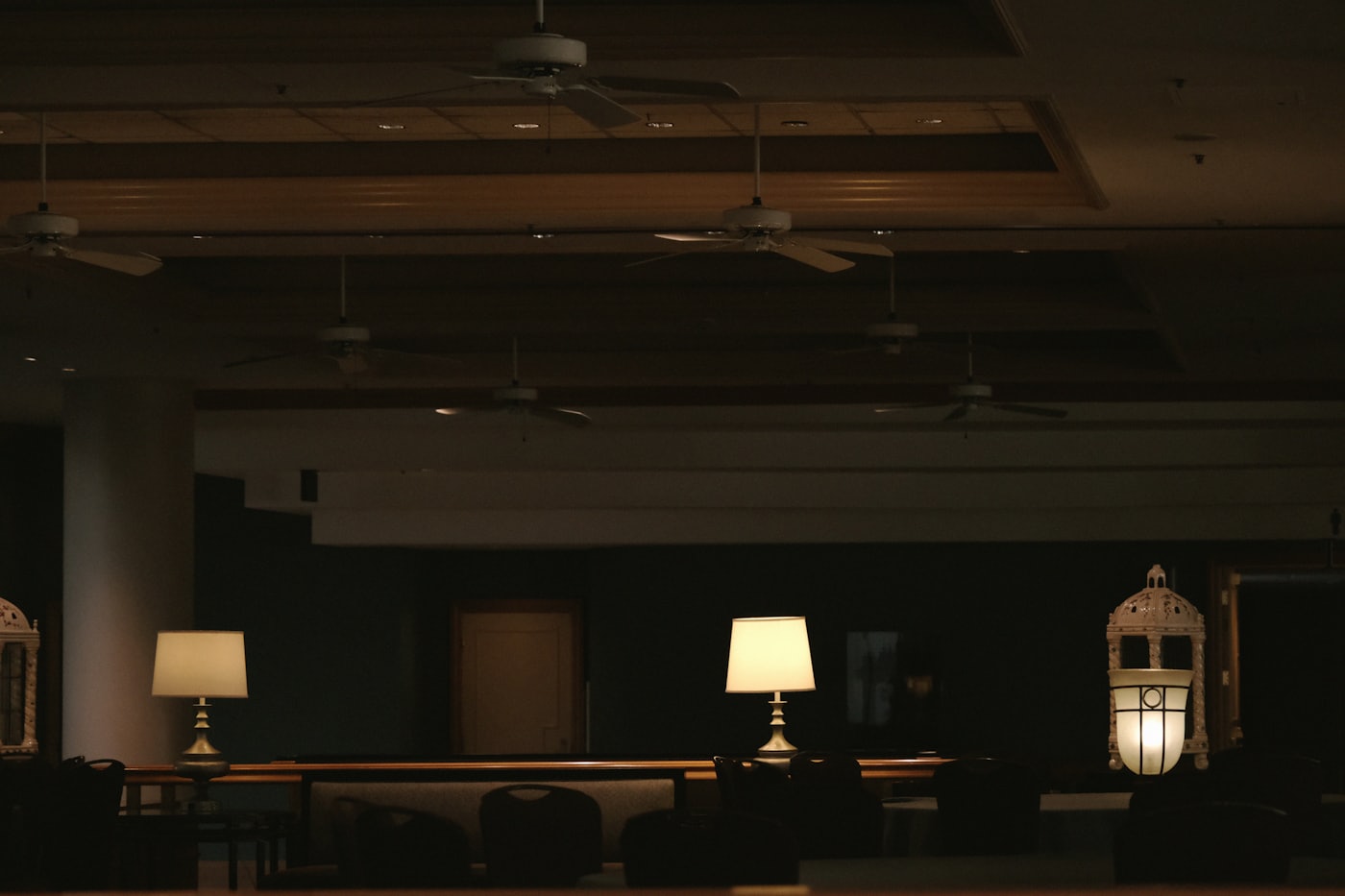 A dim, empty hotel lounge late at night, lamps still on