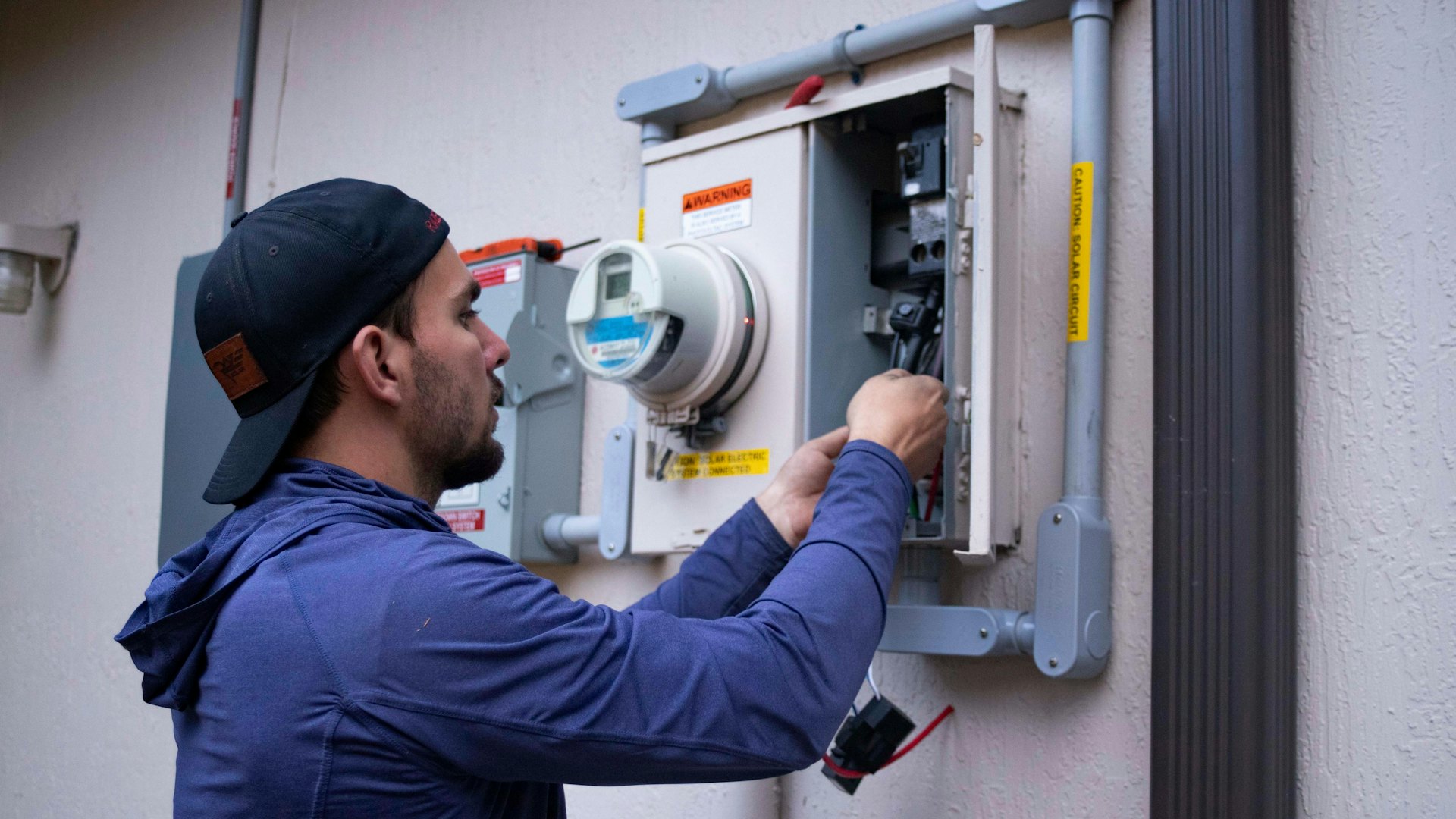 A service technician working on an equipment panel