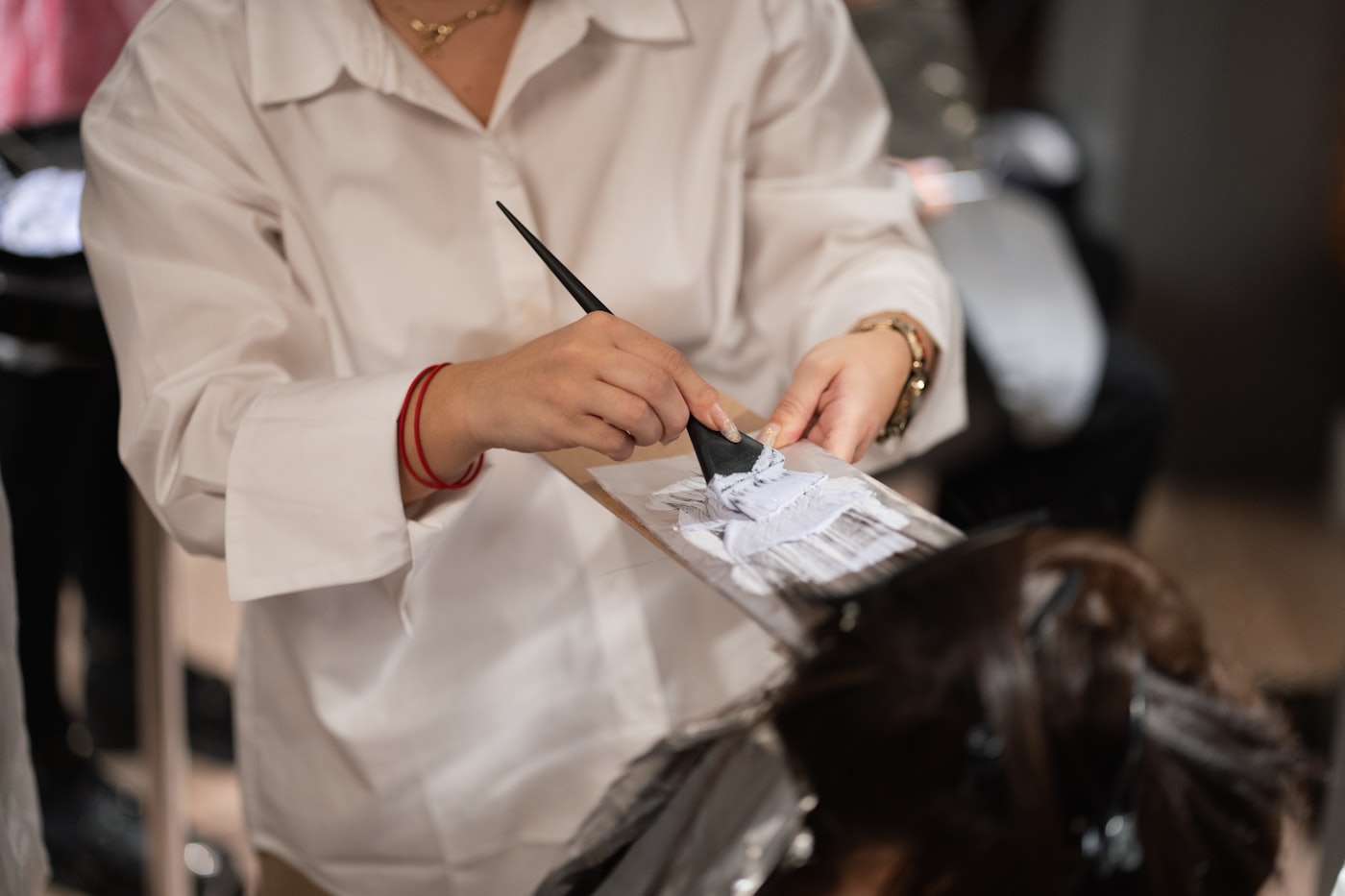 A colorist&rsquo;s hands busy mixing color at a salon station
